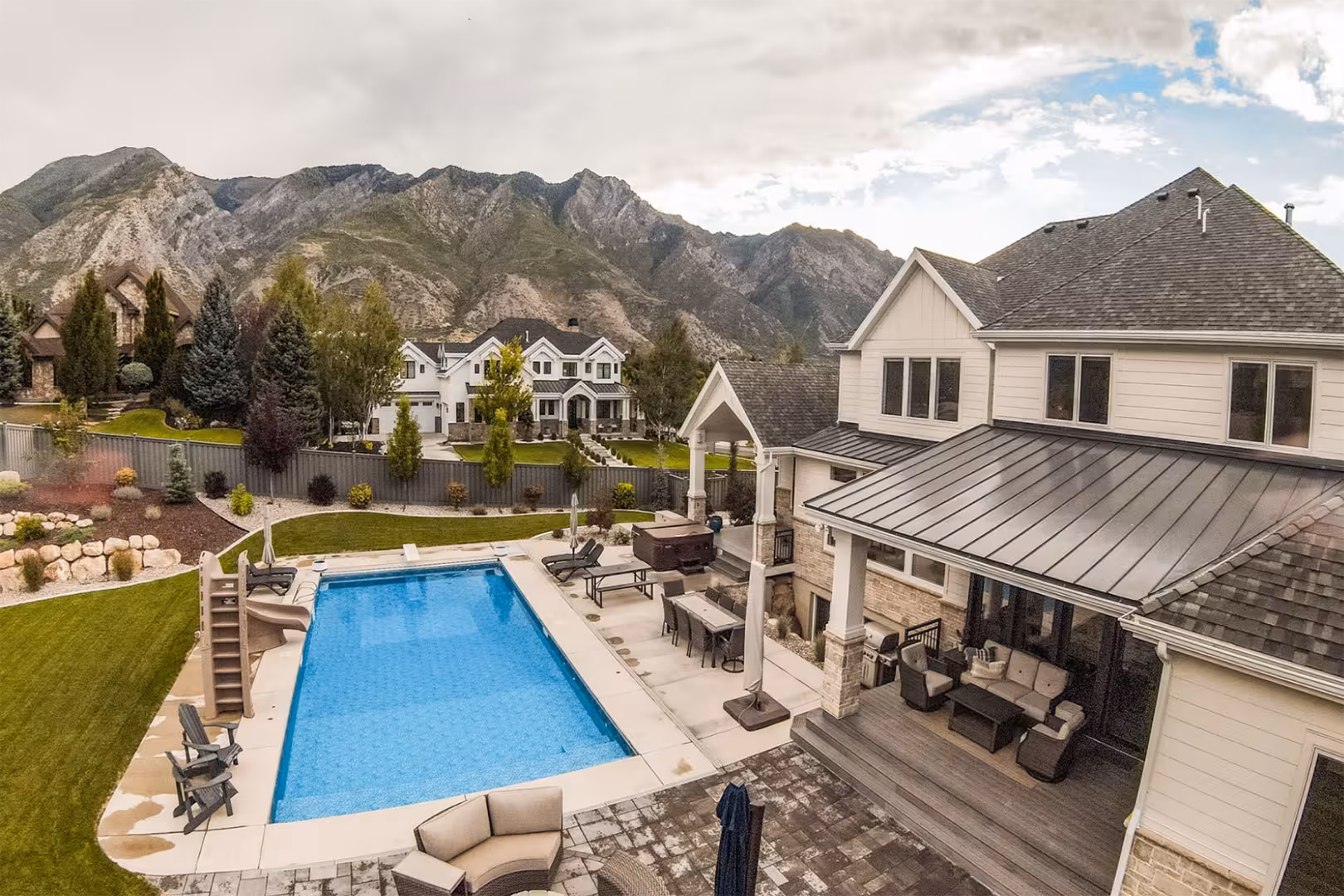 Aerial view of the Alpine home backyard with a pool, covered patio and mountain views