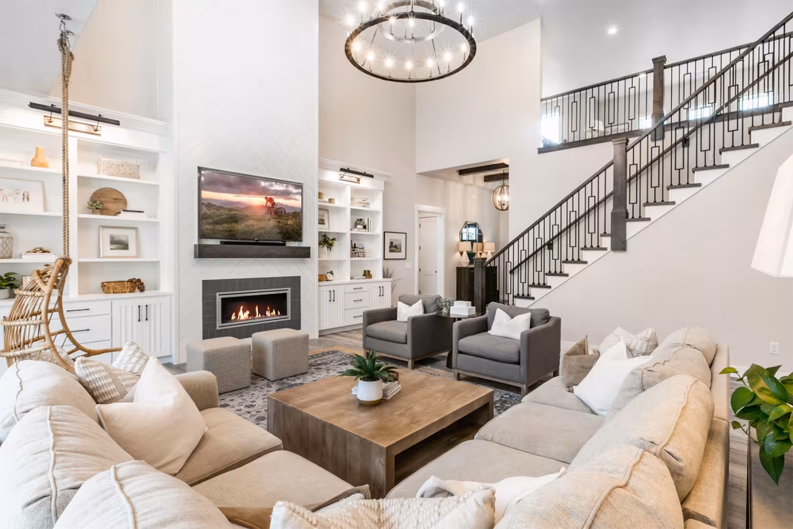 Two-story great room in the Alpine home with built-in shelves, a gas fireplace and an iron stair railing