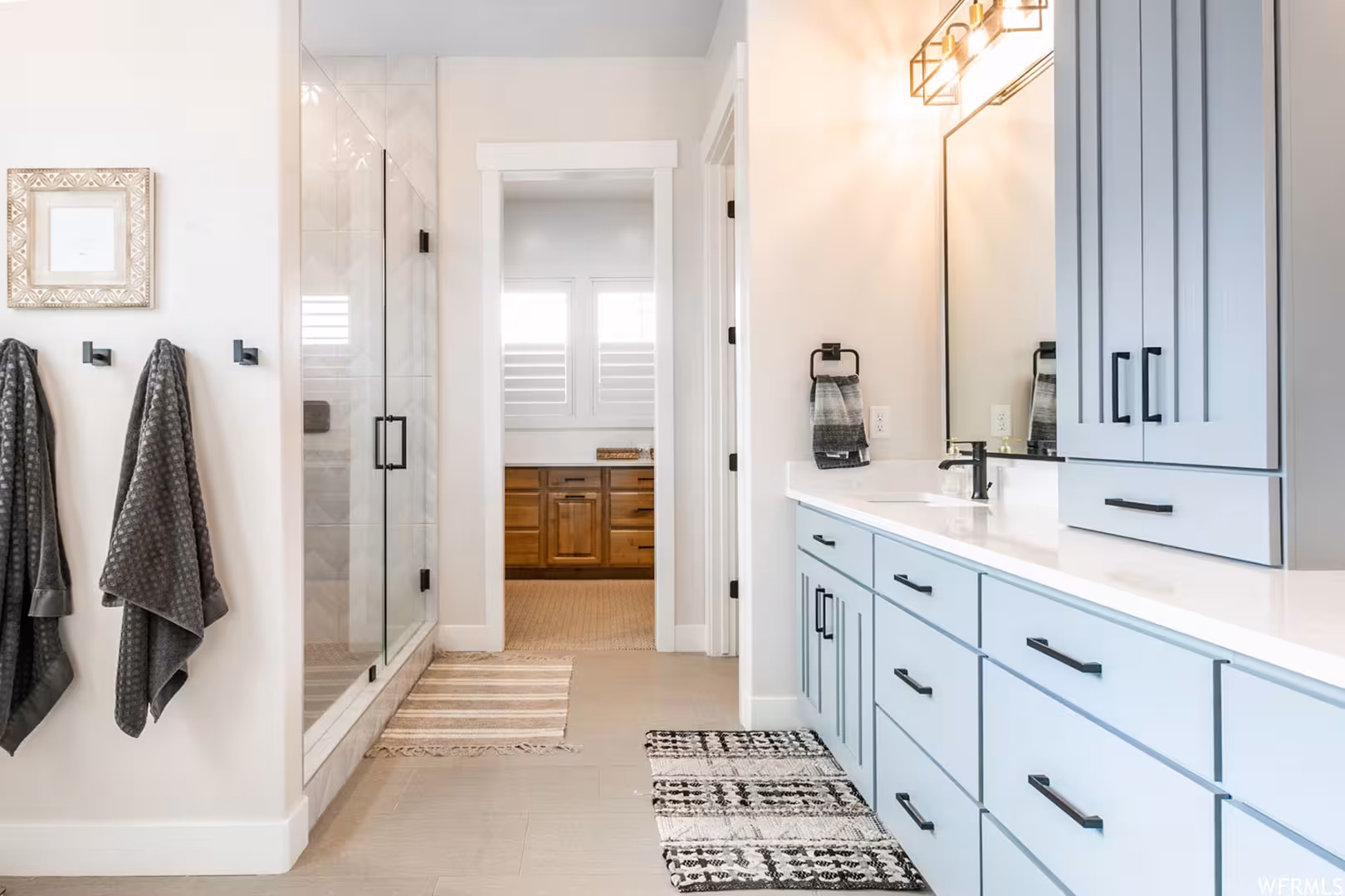 Bathroom in the Alpine home with a blue-gray vanity, glass shower and black fixtures