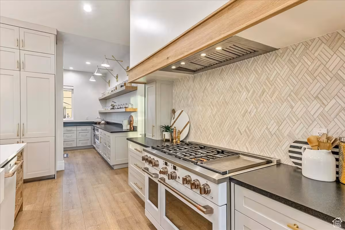 Professional gas range in the Bountiful kitchen under a wood beam hood and herringbone tile