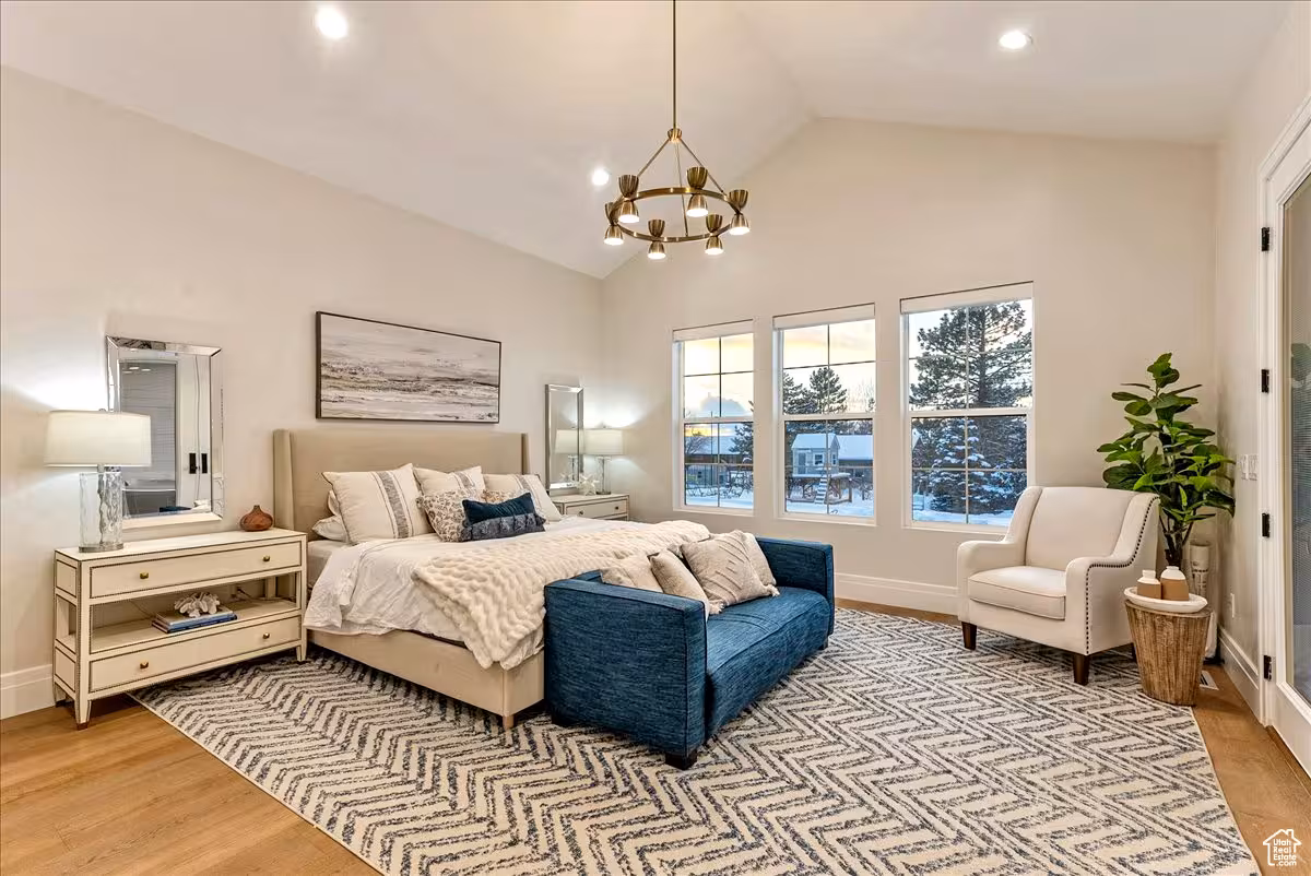 Primary bedroom in the Bountiful home with a vaulted ceiling, gold chandelier and three windows