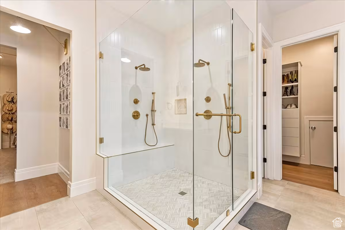 Glass walk-in shower with brass fixtures and a bench, next to a closet in the Bountiful home