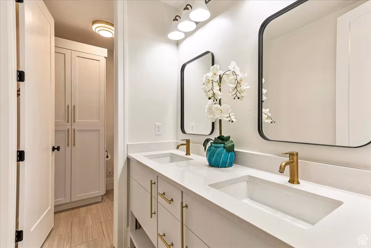 Bathroom in the Bountiful home with a white double vanity, gold faucets and black-framed mirrors