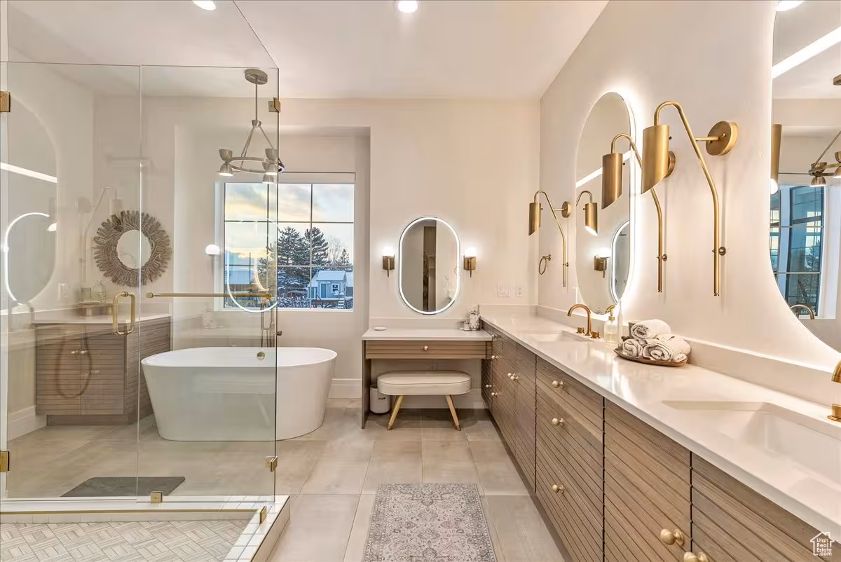 Bountiful primary bathroom with a fluted wood double vanity, makeup desk and glass shower