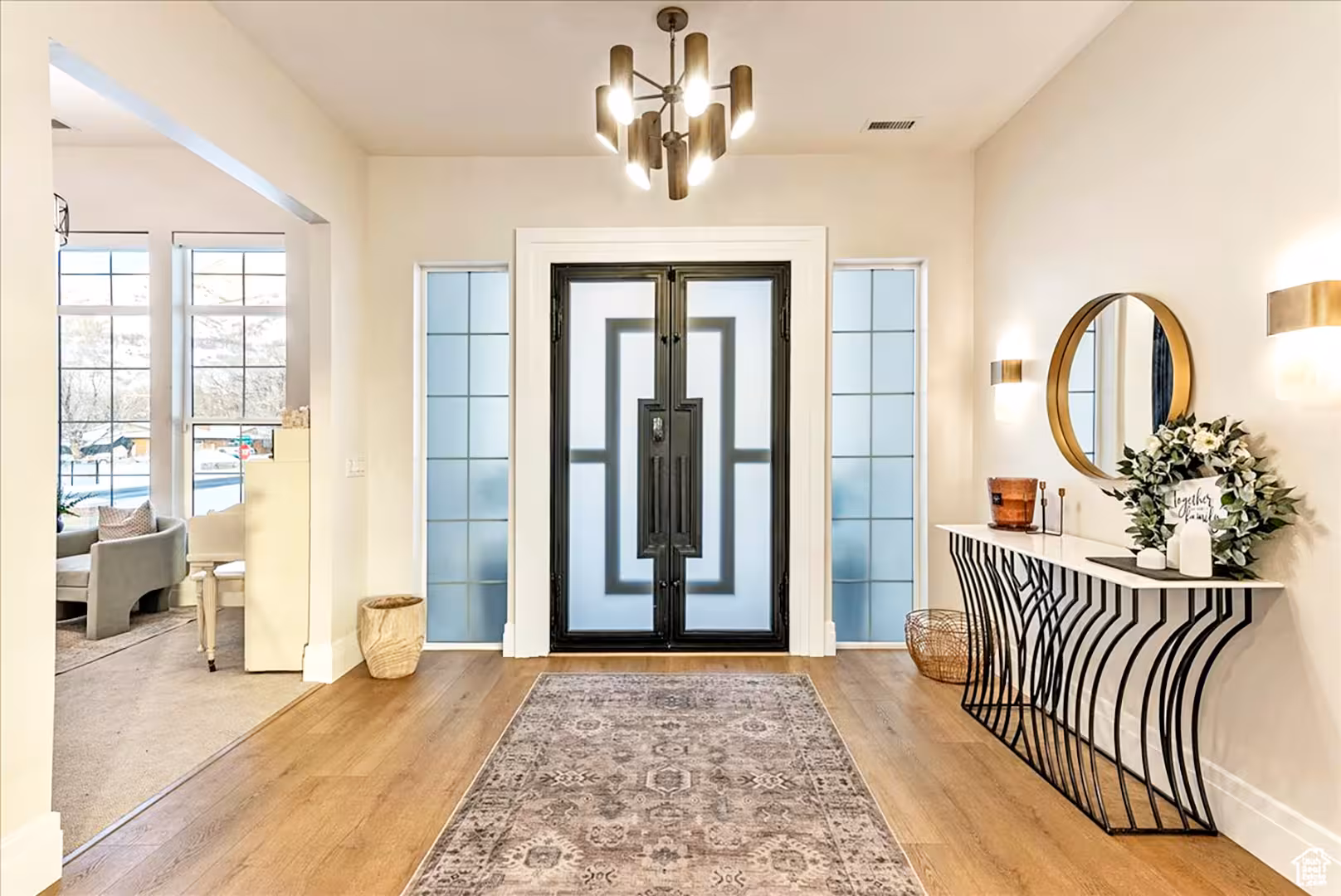 Foyer in the Bountiful home with a black iron double door, frosted sidelights and a gold chandelier