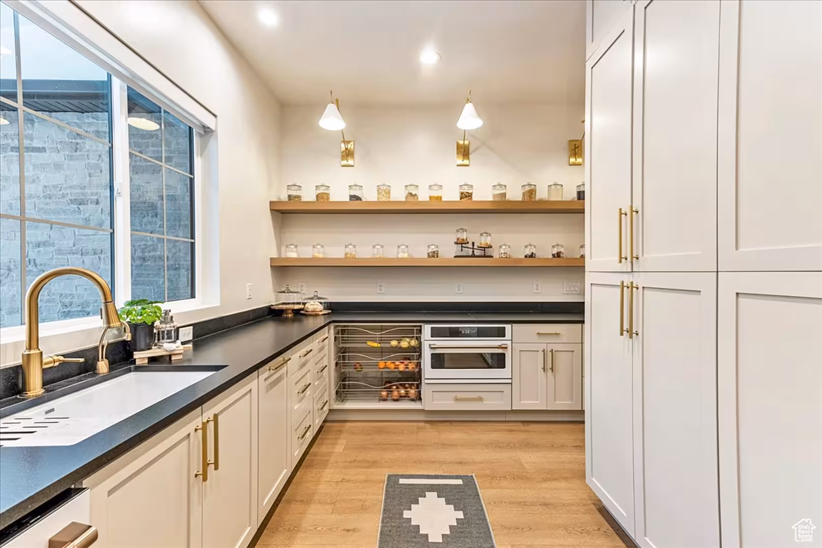 Butler's pantry in the Bountiful home with open wood shelves, a brass faucet and dark counters