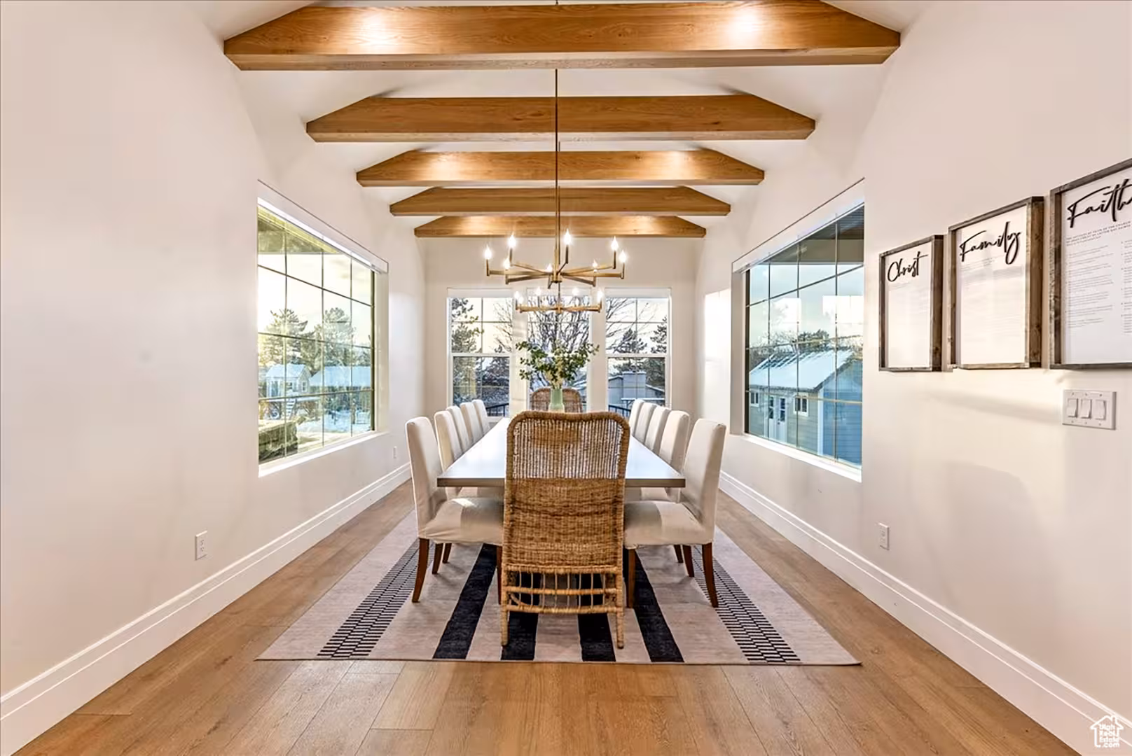 Dining room in the Bountiful home with exposed wood beams, a long table and windows on both sides