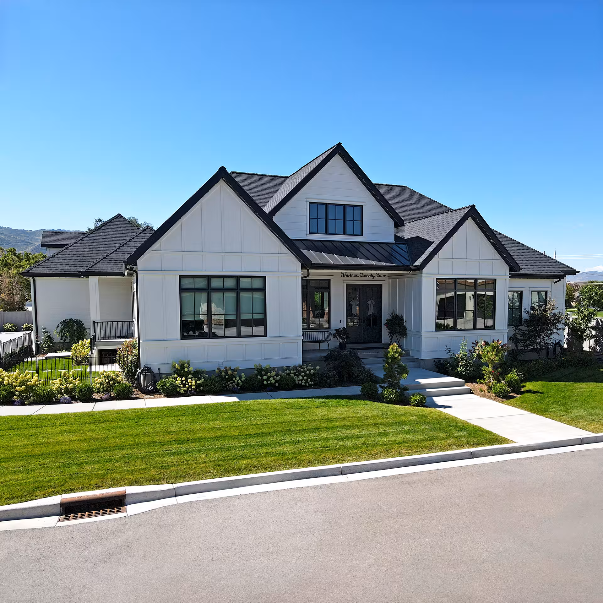 Front of the Brighton home with black-framed windows, a metal porch roof and a striped lawn
