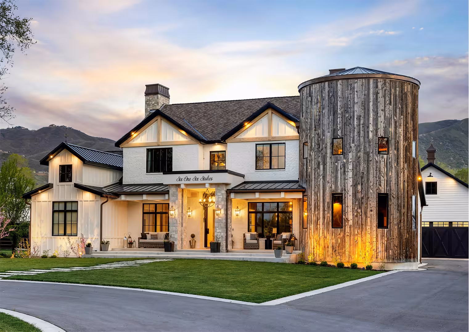 Front of the Draper home at dusk with white siding, black trim and a weathered wood silo tower