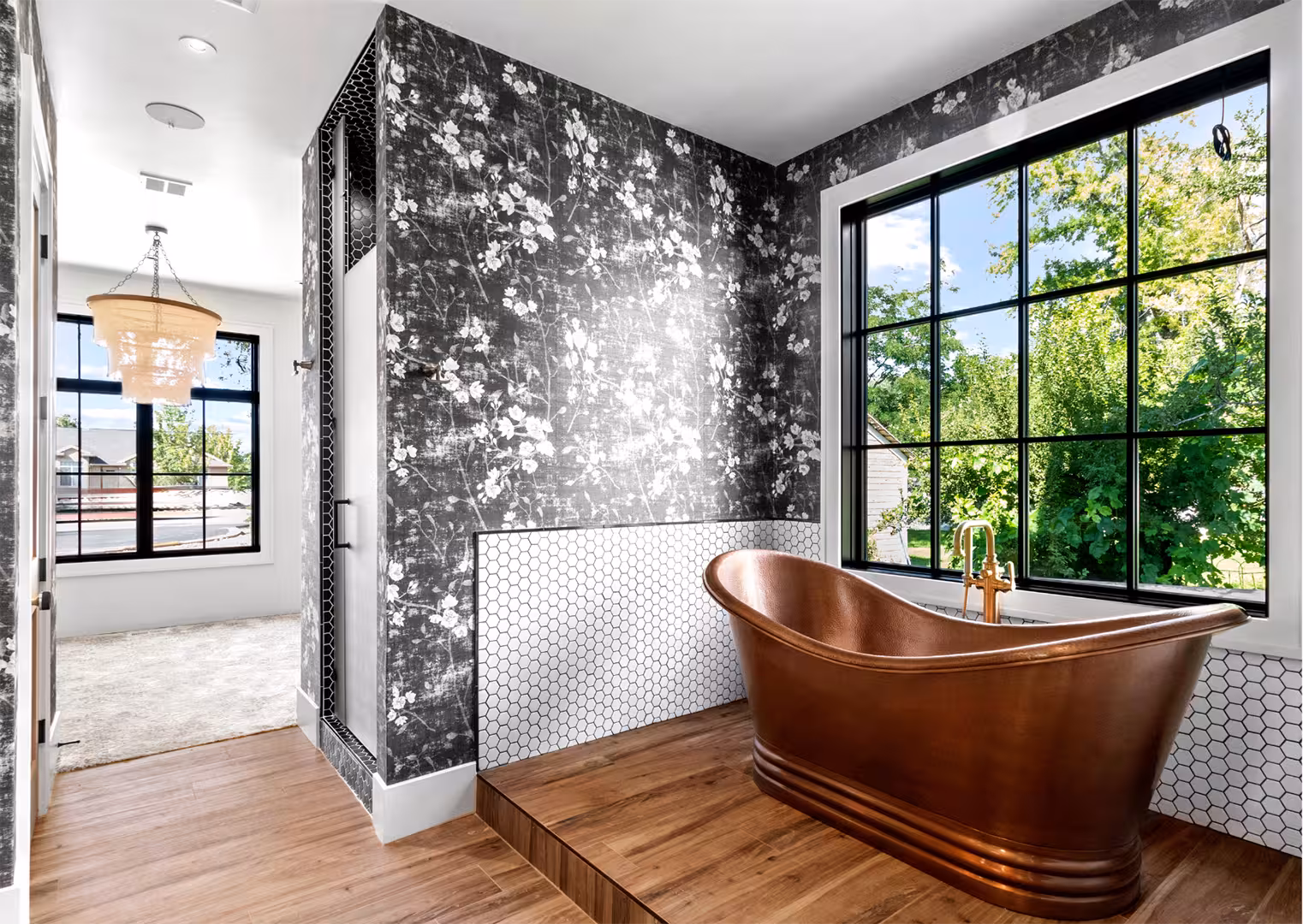 Copper freestanding tub on a raised wood platform beside a large black-framed window in the Draper home