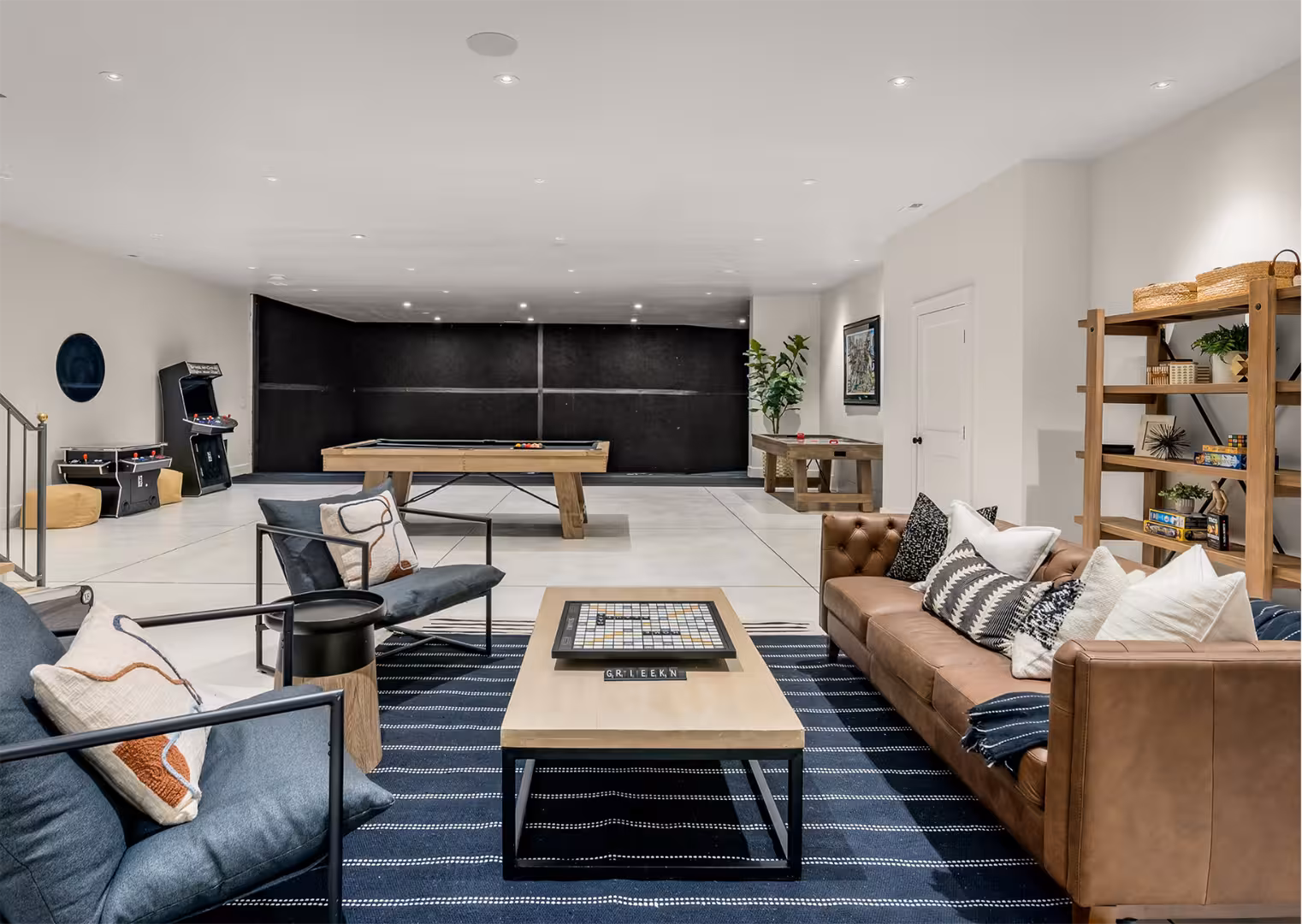 Basement family room in the Draper home with a pool table, arcade game and leather sofa