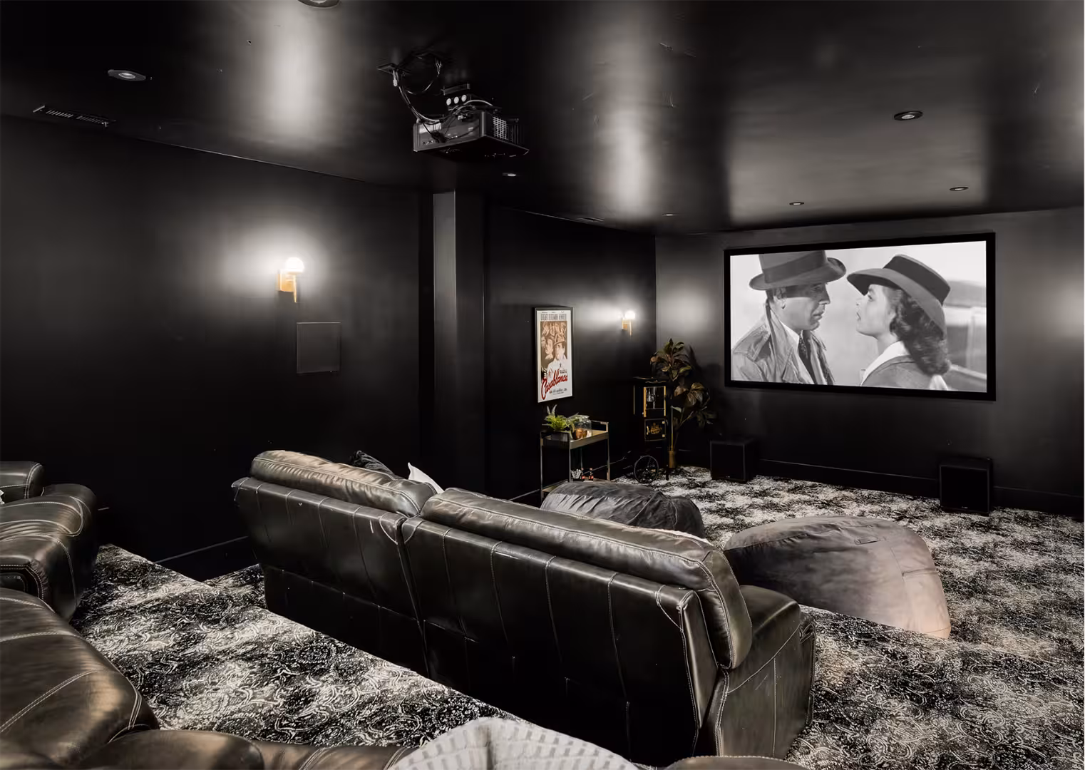 Home theater in the Draper home with black walls, leather seating and a projection screen