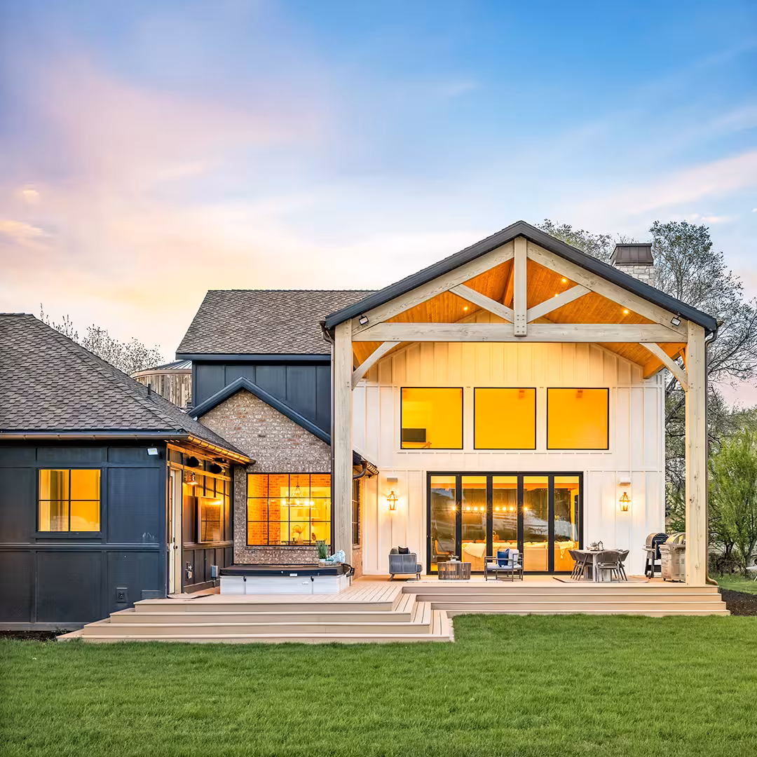 Rear of the Draper home with a timber-framed gable, tall windows and a wide wood deck