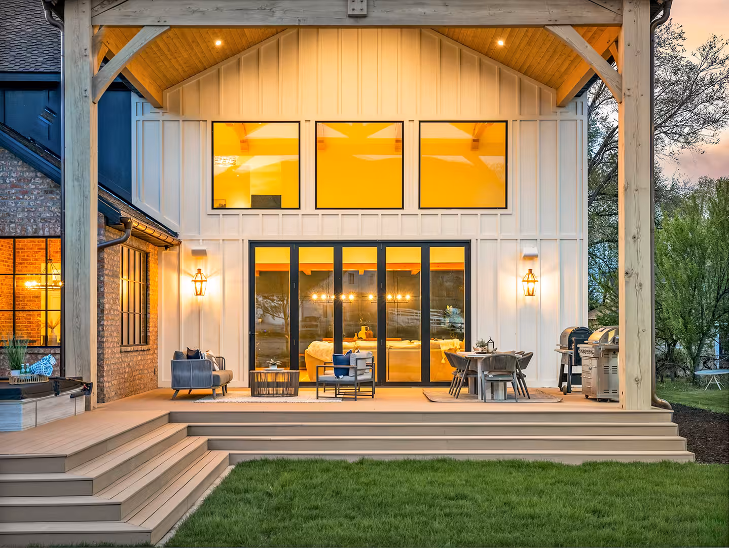 Covered patio of the Draper home with timber posts, a vaulted wood ceiling and black-framed doors
