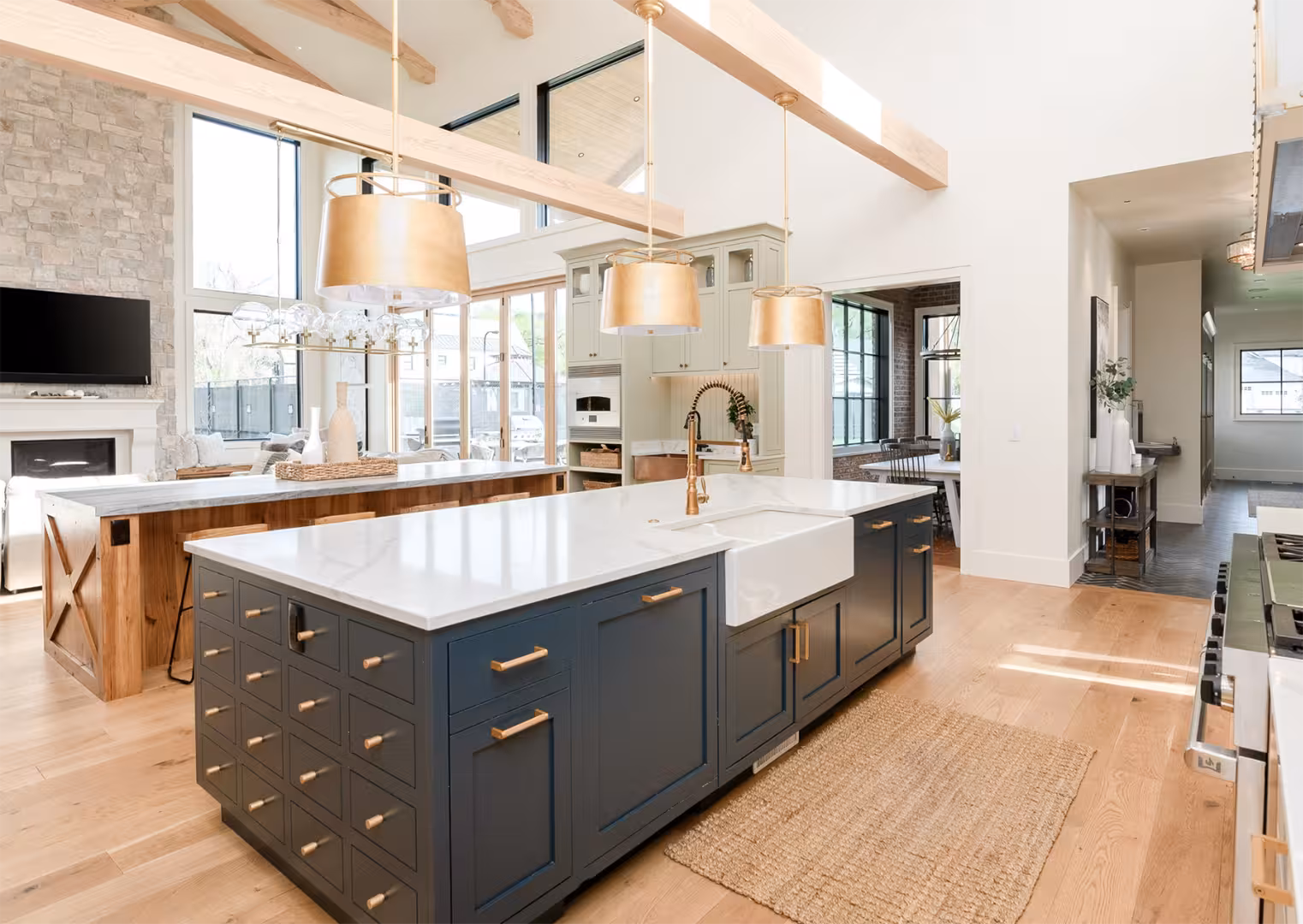 Navy kitchen island with a white farmhouse sink and brass hardware in the Draper home