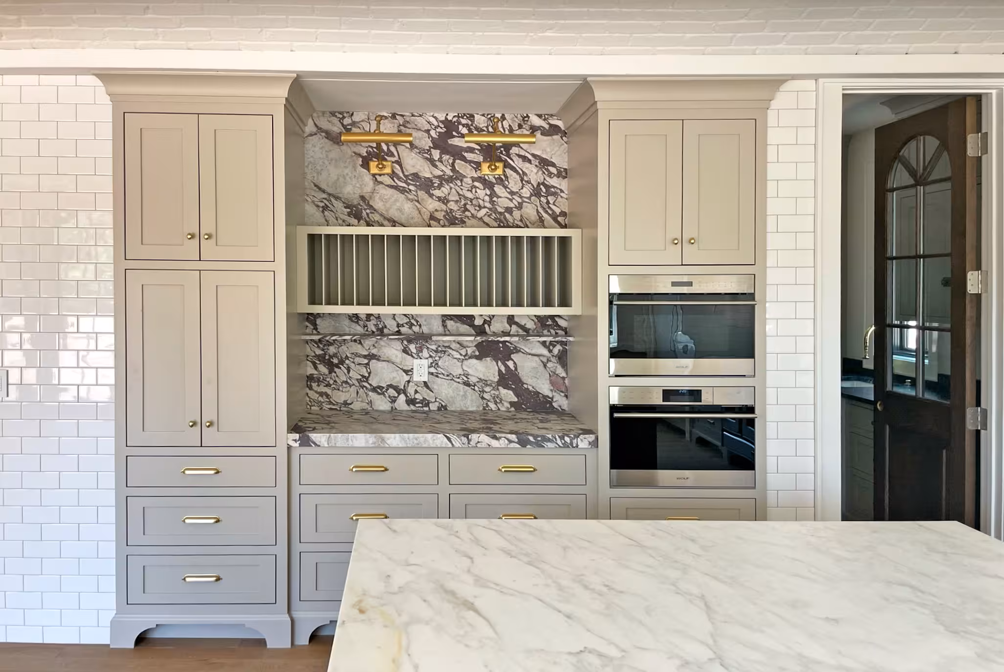 Built-in coffee bar in the Holladay kitchen with a bold marble backsplash and a plate rack