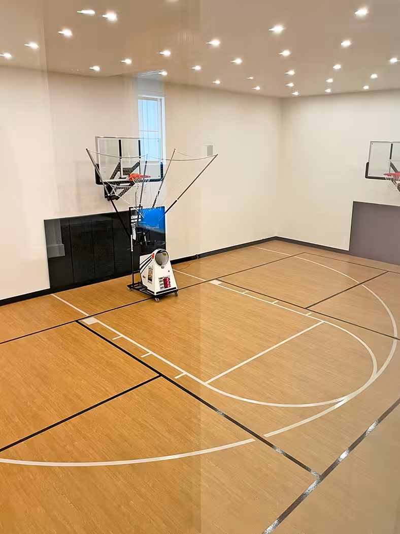 Indoor basketball court in the Holladay home with wood flooring and a rebounding machine