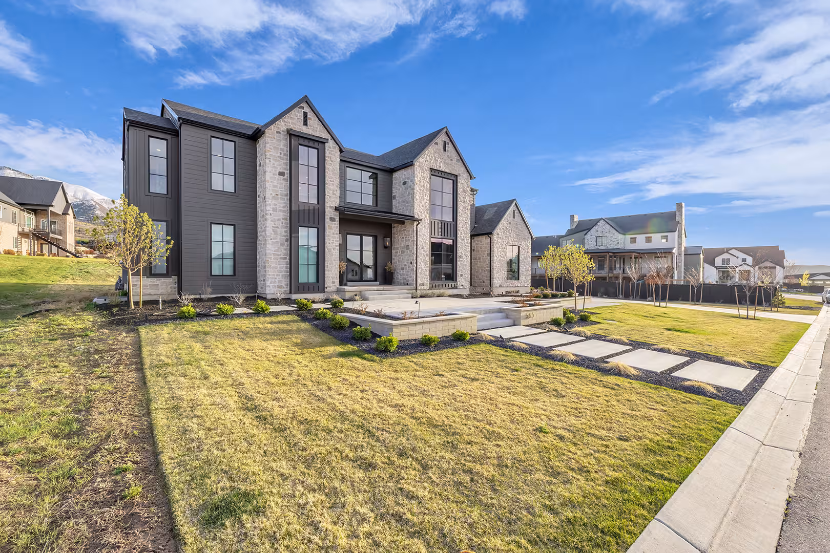 Front of the Elk Ridge home with dark siding, stone gables and a wide front lawn