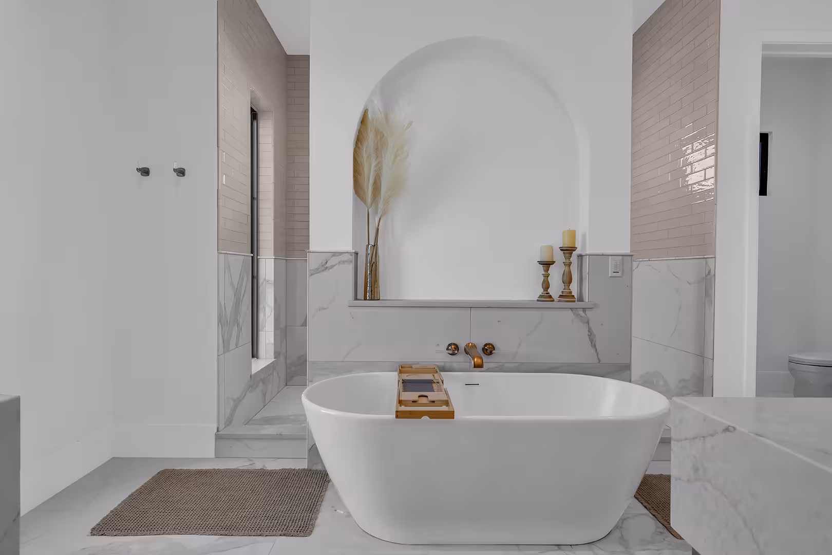 Freestanding tub in front of an arched shower niche with marble walls in the Elk Ridge home