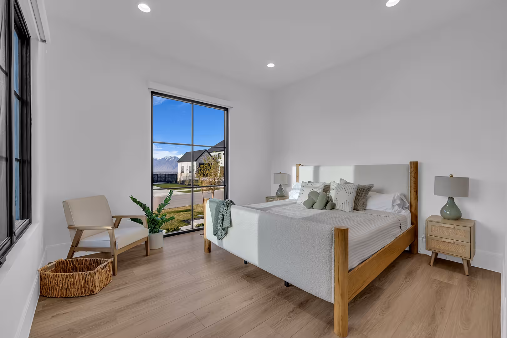 Bright bedroom in the Elk Ridge home with a tall black-framed window and a wood bed