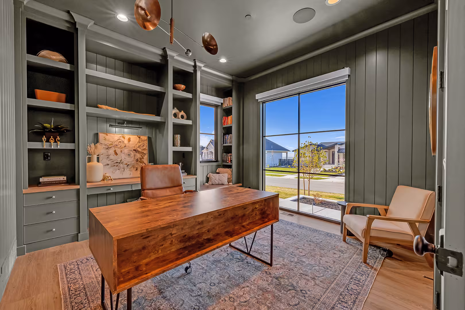 Elk Ridge home office with green built-in shelves, paneled walls and a wood desk