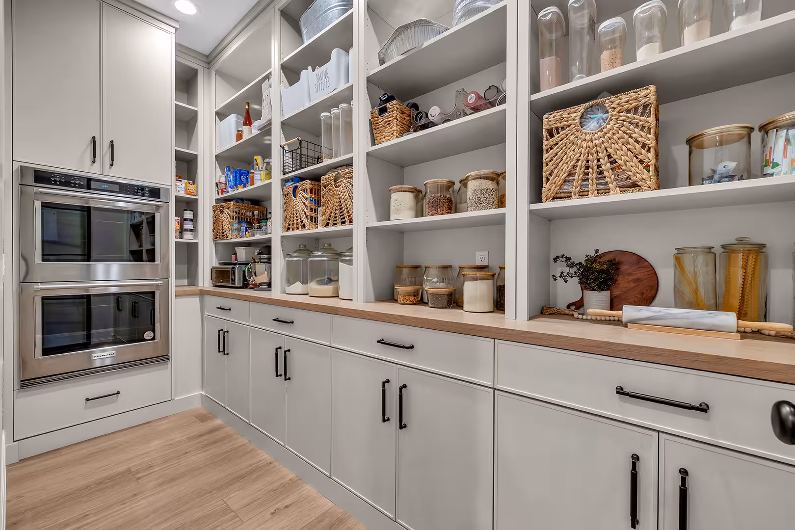 Walk-in pantry in the Elk Ridge home with open shelves, double wall ovens and a wood counter