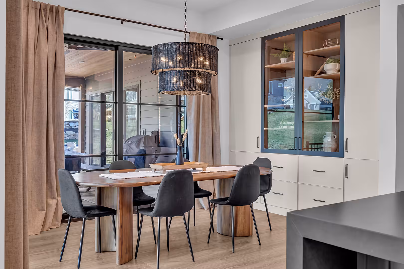 Dining area in the Elk Ridge home with a wood table, woven pendant and a glass display cabinet