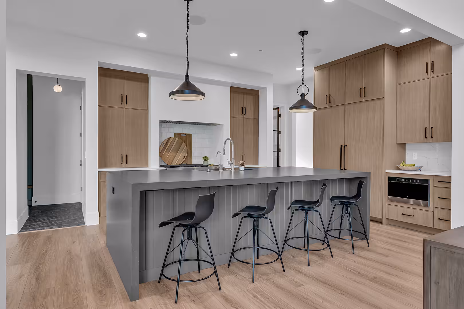 Elk Ridge kitchen island with a waterfall counter and paneled gray base, backed by wood cabinets