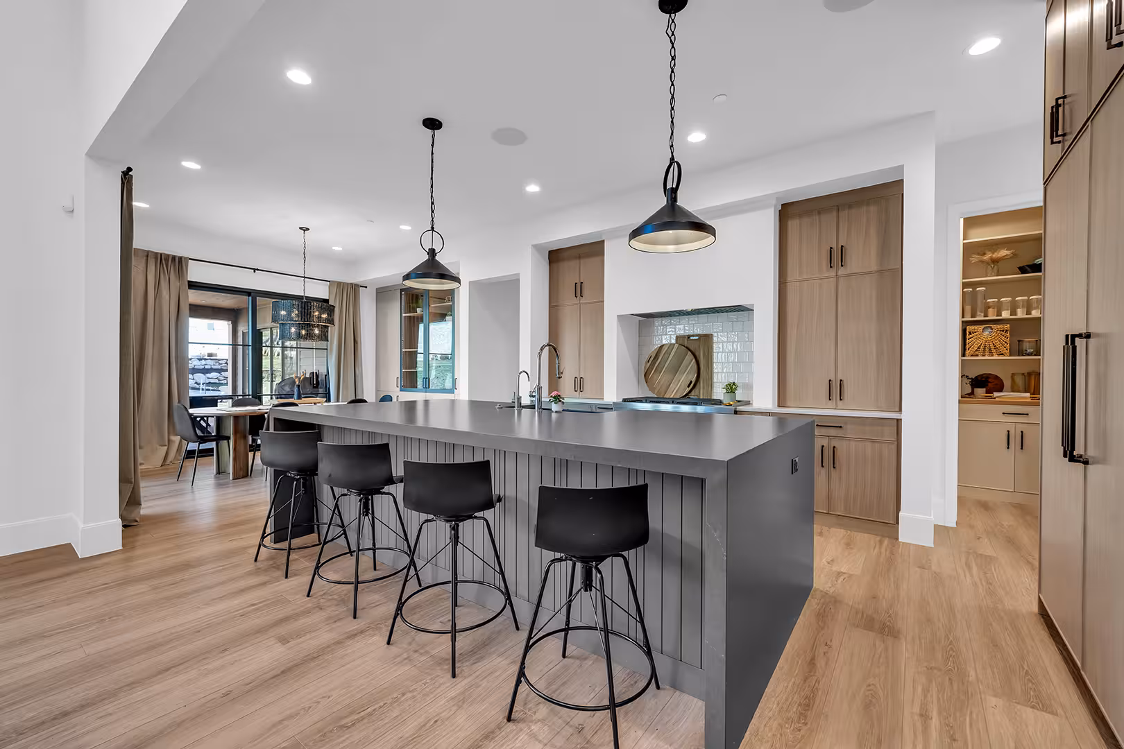 Elk Ridge home kitchen with a dark gray island, black counter stools and wood cabinetry