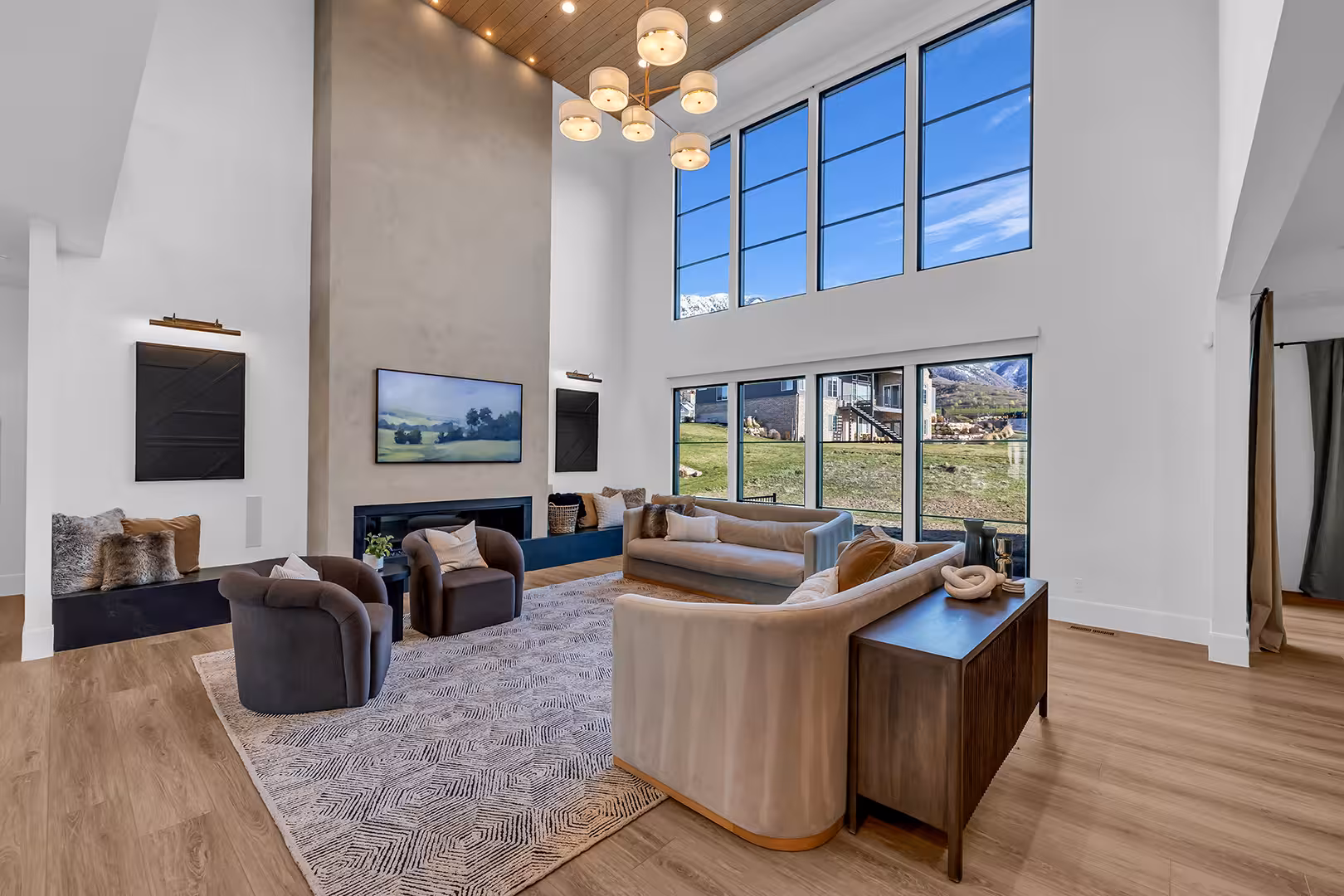 Two-story living room in the Elk Ridge home with a plaster fireplace wall and tall windows