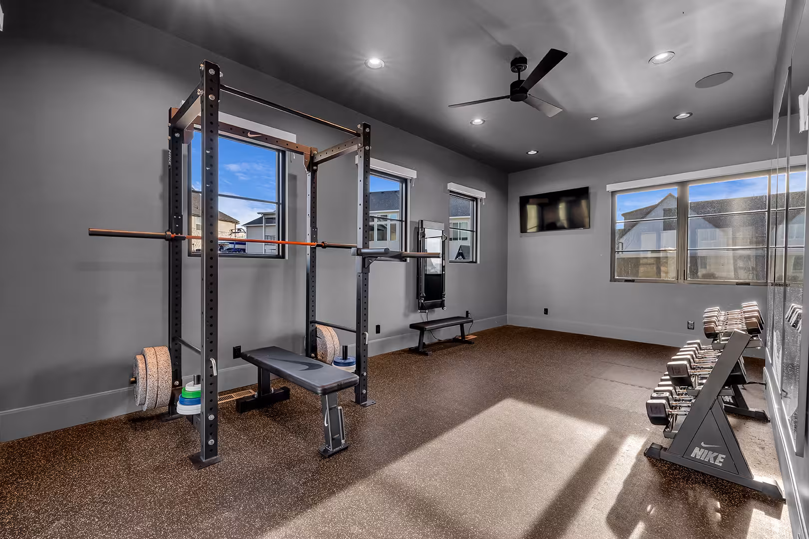 Home gym in the Elk Ridge home with a squat rack, dumbbells and gray walls
