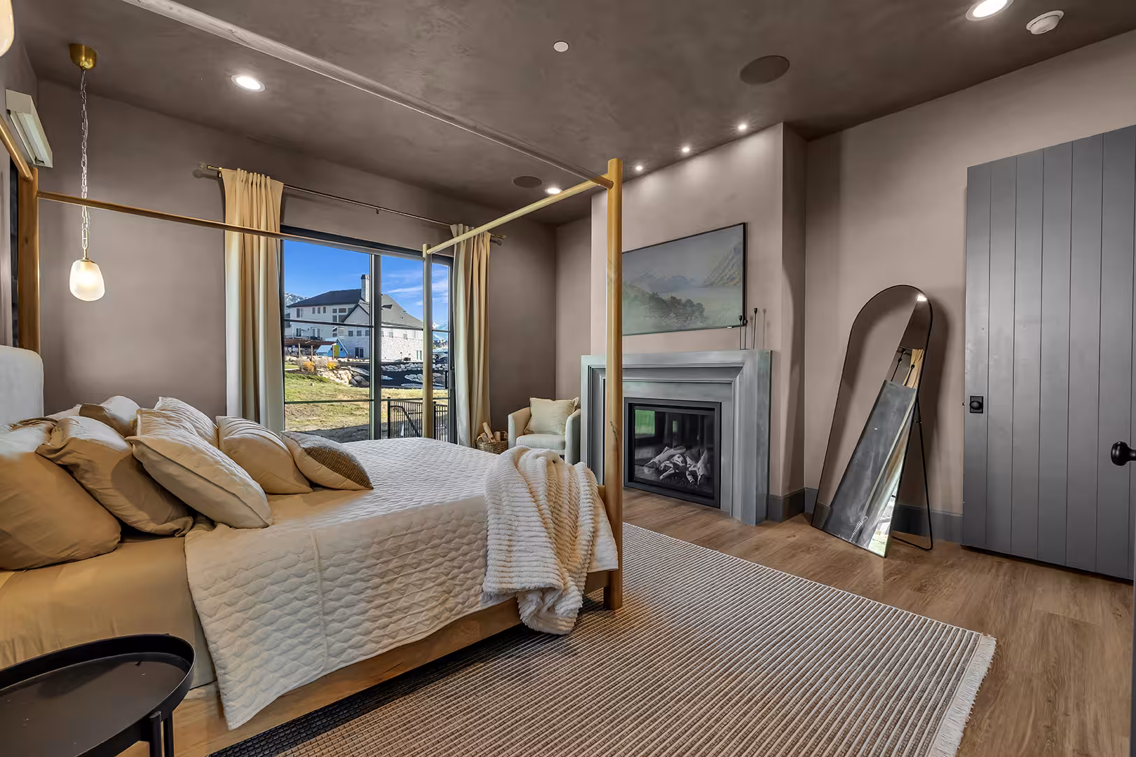 Primary bedroom in the Elk Ridge home with a brass canopy bed, a fireplace and a dark ceiling