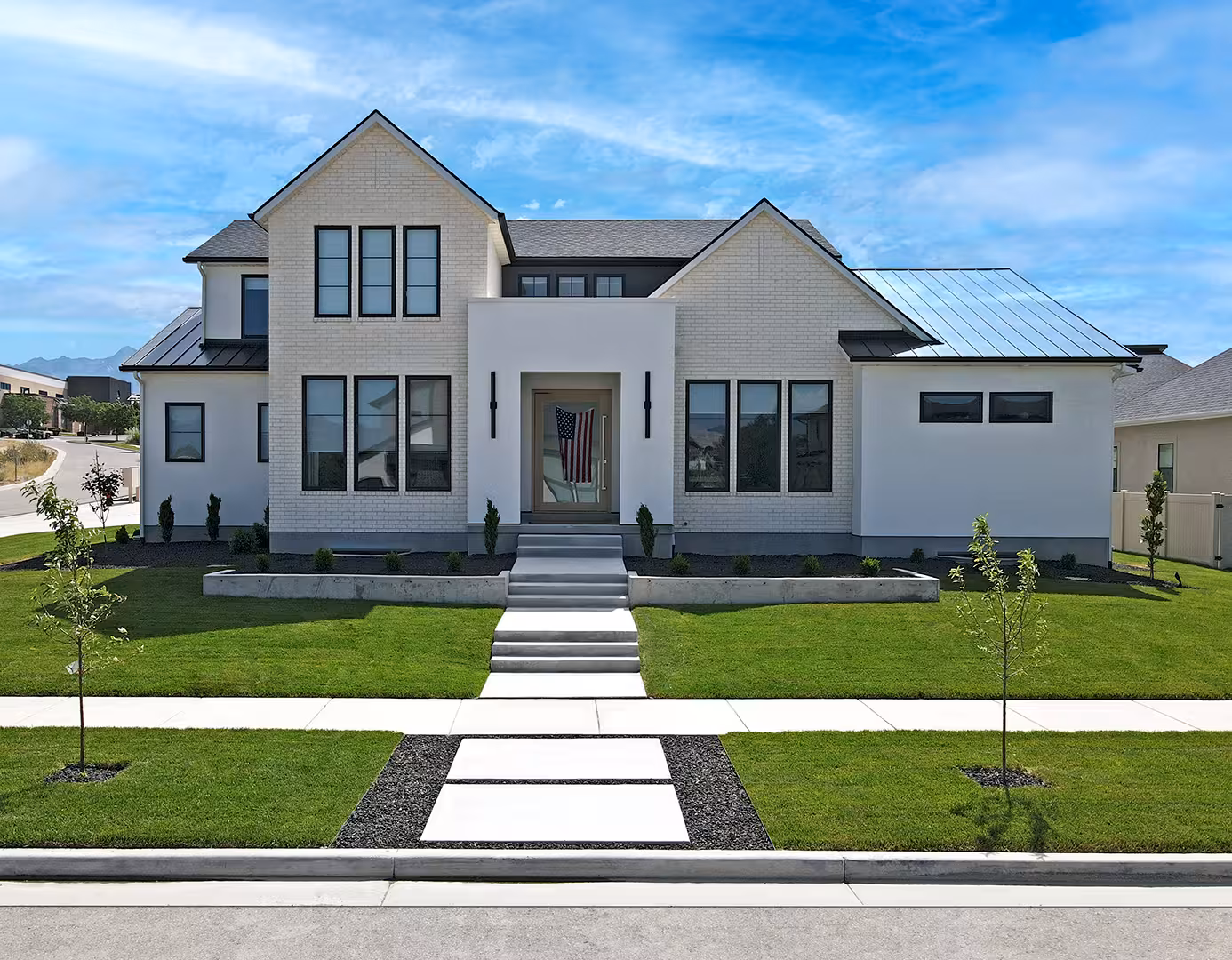 Front of the Jordan home with white brick, a metal roof accent and a wide front walk