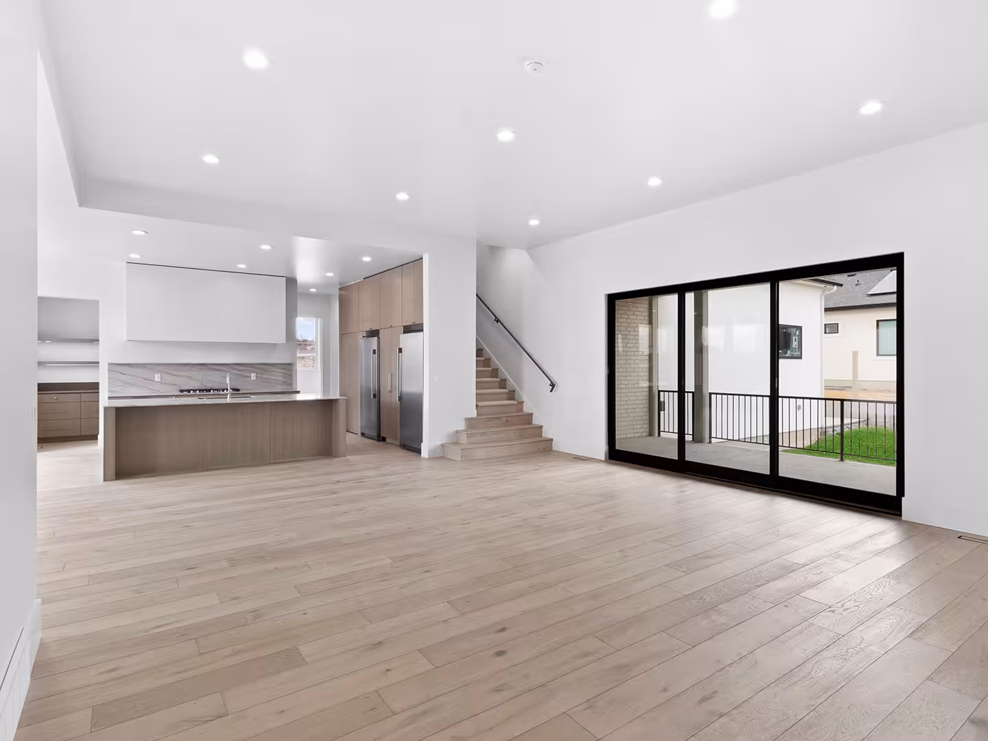 Open main floor of the Jordan home with light wood floors and black sliding glass doors