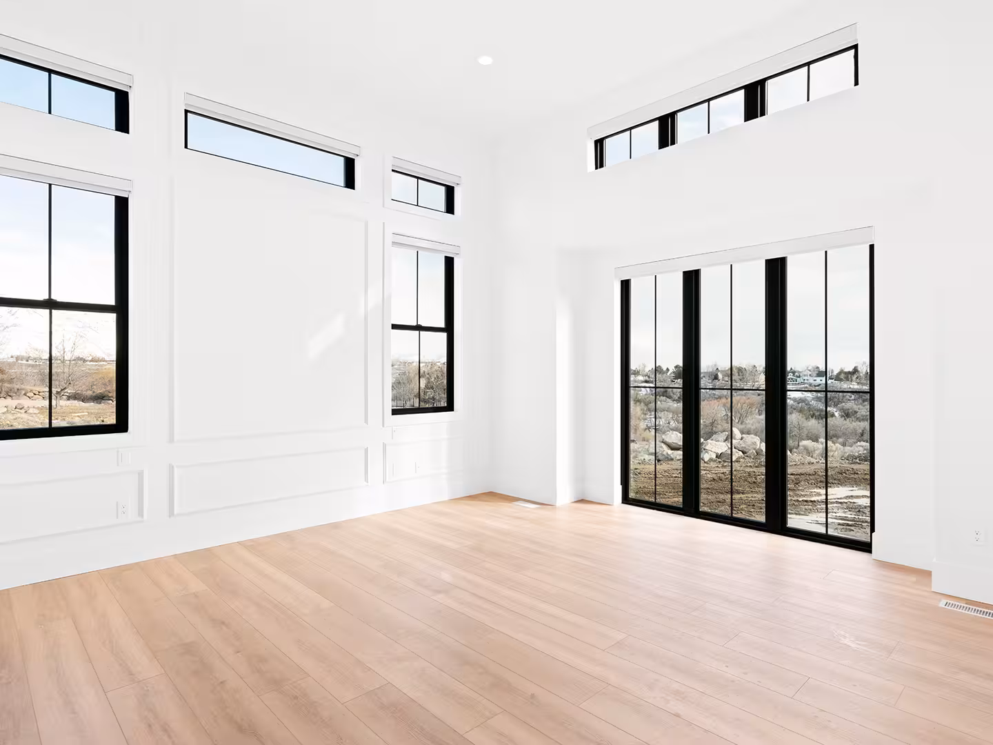 Bright room in the Lehi home with paneled walls, transom windows and black glass doors