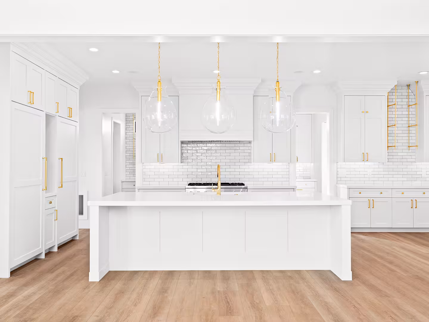 Lehi home kitchen island facing the range wall with white subway tile and three glass pendants