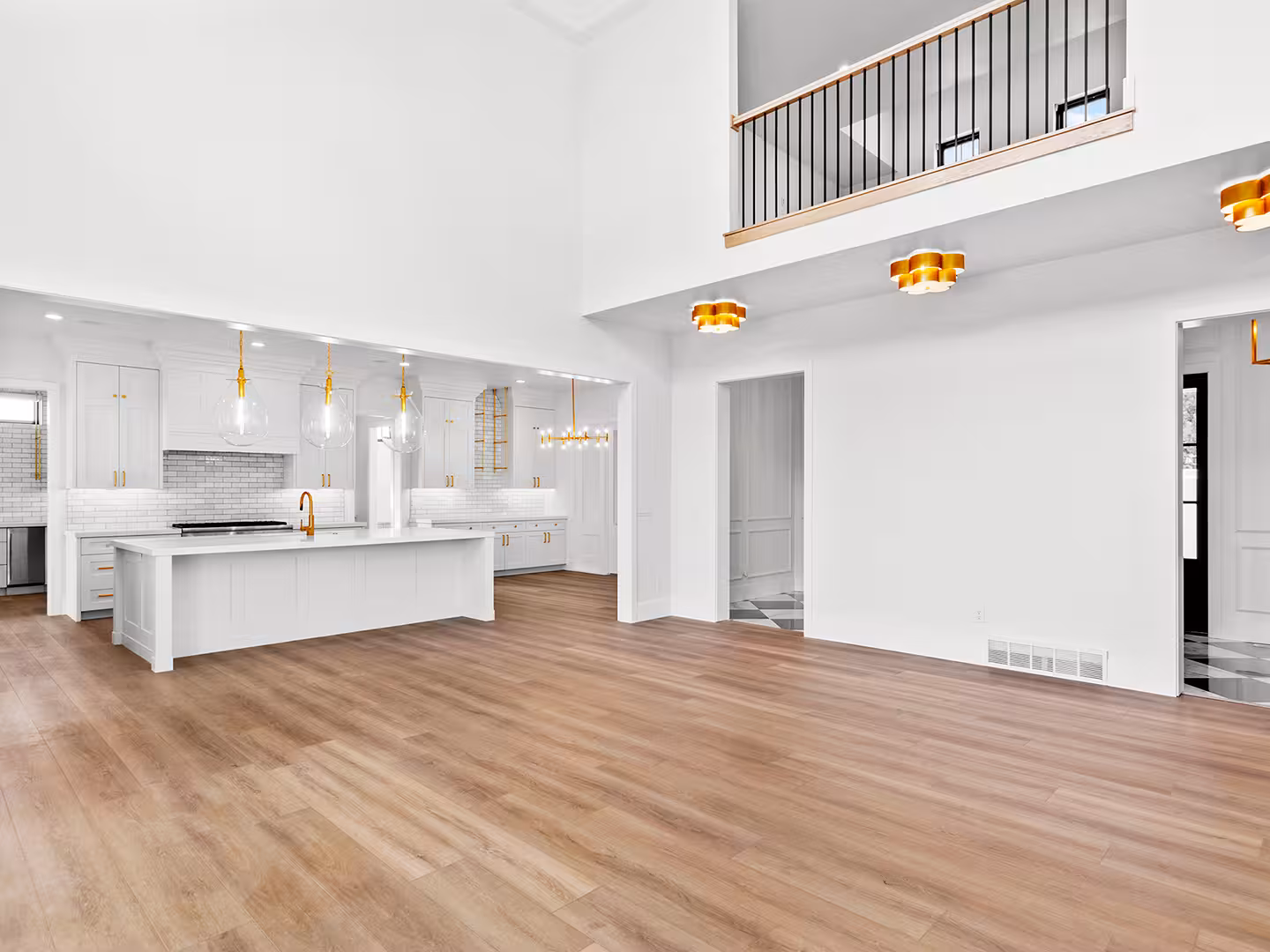 Open great room and white kitchen in the Lehi home with an upstairs loft railing