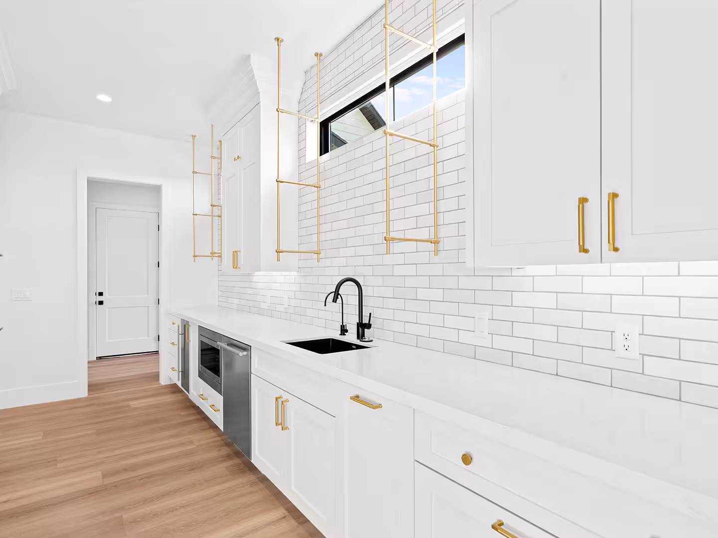 Lehi home butler's pantry with white subway tile, brass hanging shelves and a black faucet