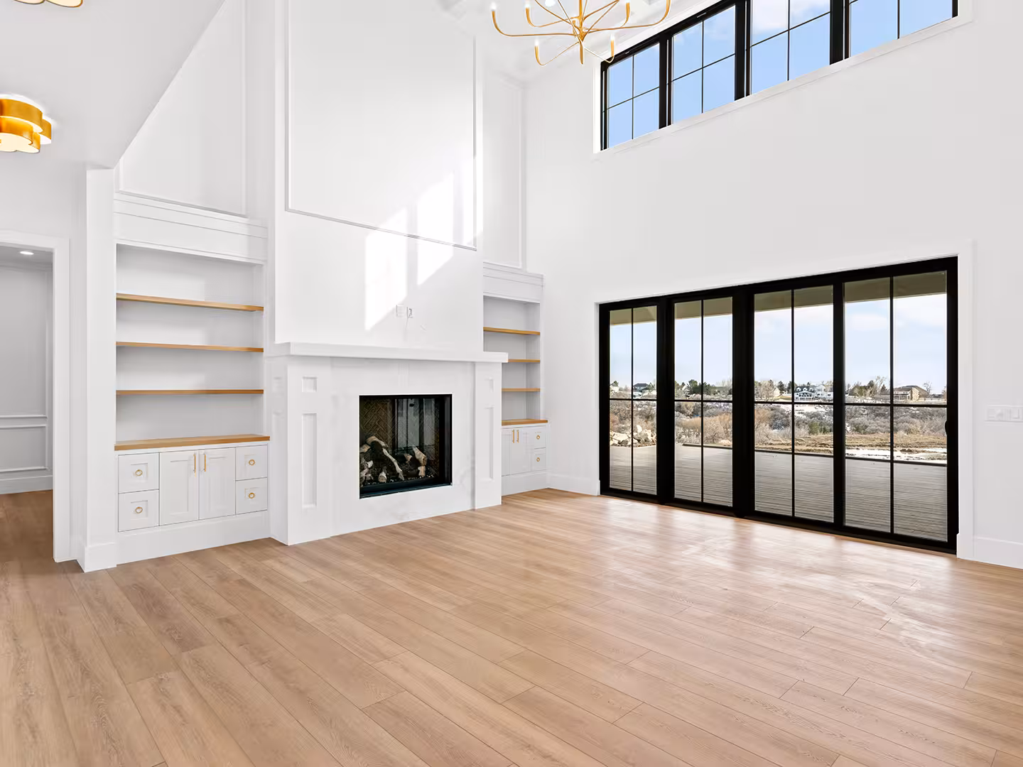 Lehi home living room with a white fireplace, built-in shelves and black sliding glass doors