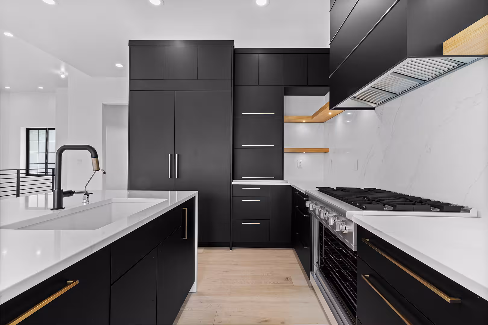 Black kitchen cabinets with brass trim and a gas range in the Meadow home