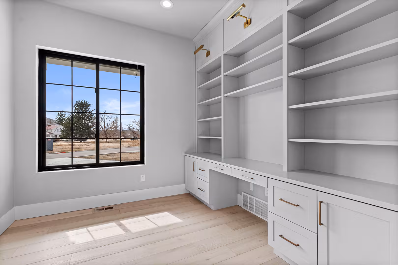 Office in the Meadow home with white built-in shelves, a desk and a black-framed window