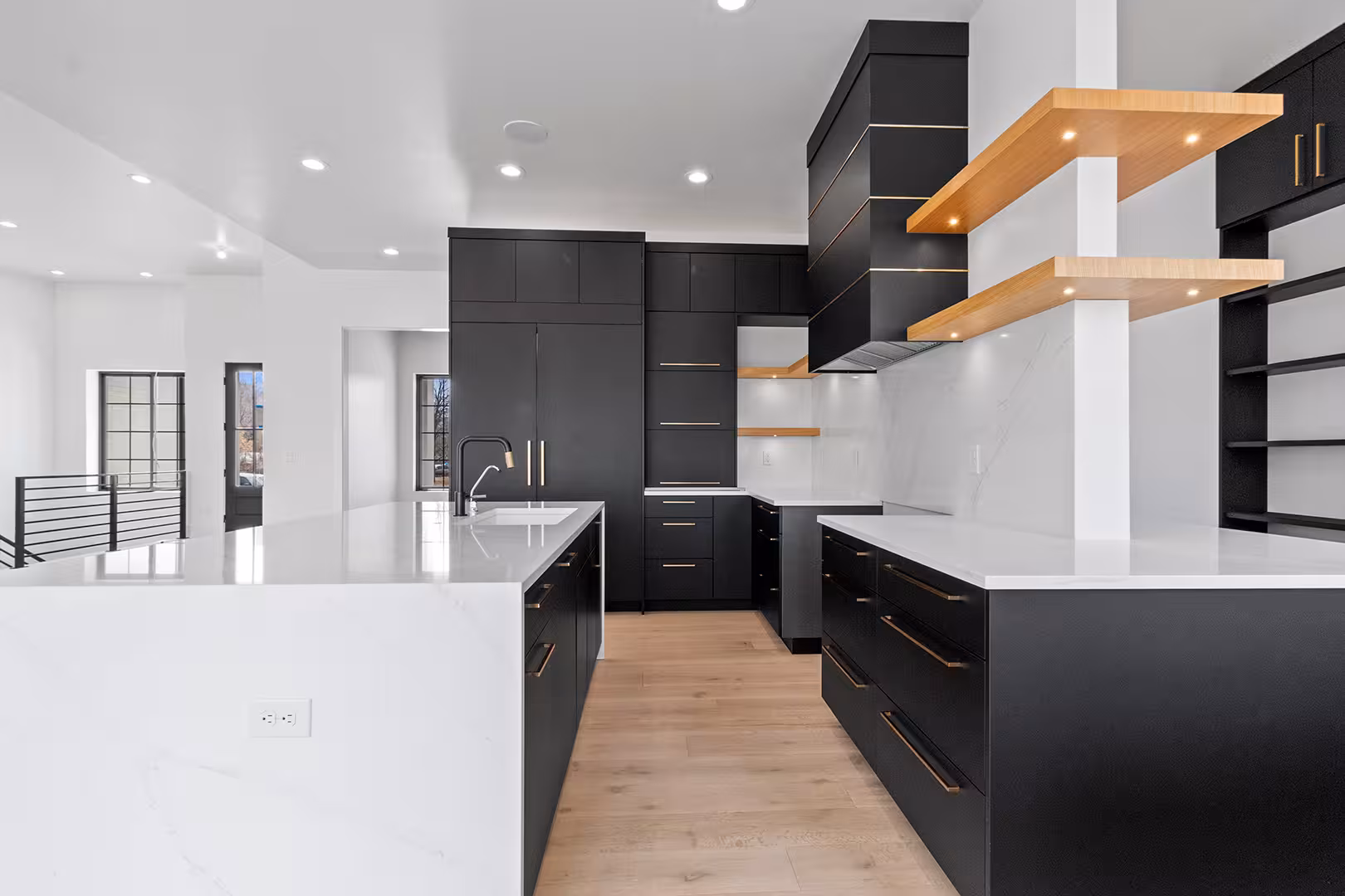 Meadow kitchen with two islands, black cabinetry and lit floating wood shelves