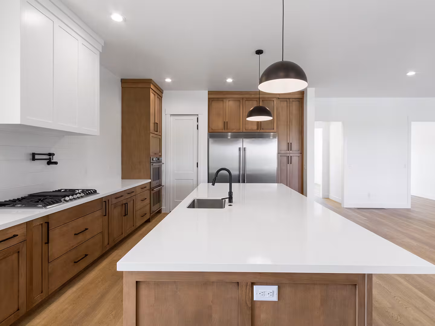 White quartz island with a black faucet in the Paradise kitchen, with stained wood cabinets