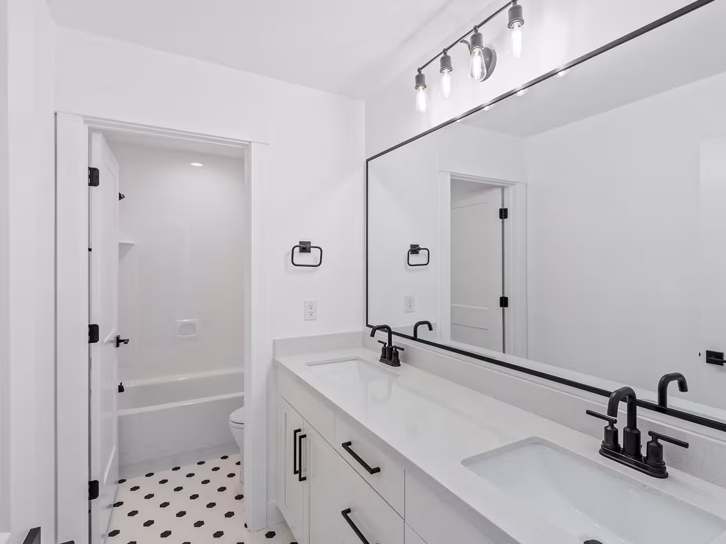 Paradise home bathroom with a white double vanity, a long black-framed mirror and black fixtures