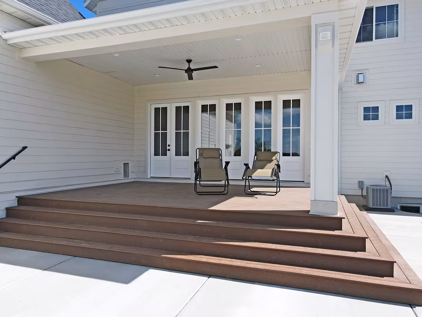 Covered back porch of the Paradise home with wide wood steps and a row of French doors