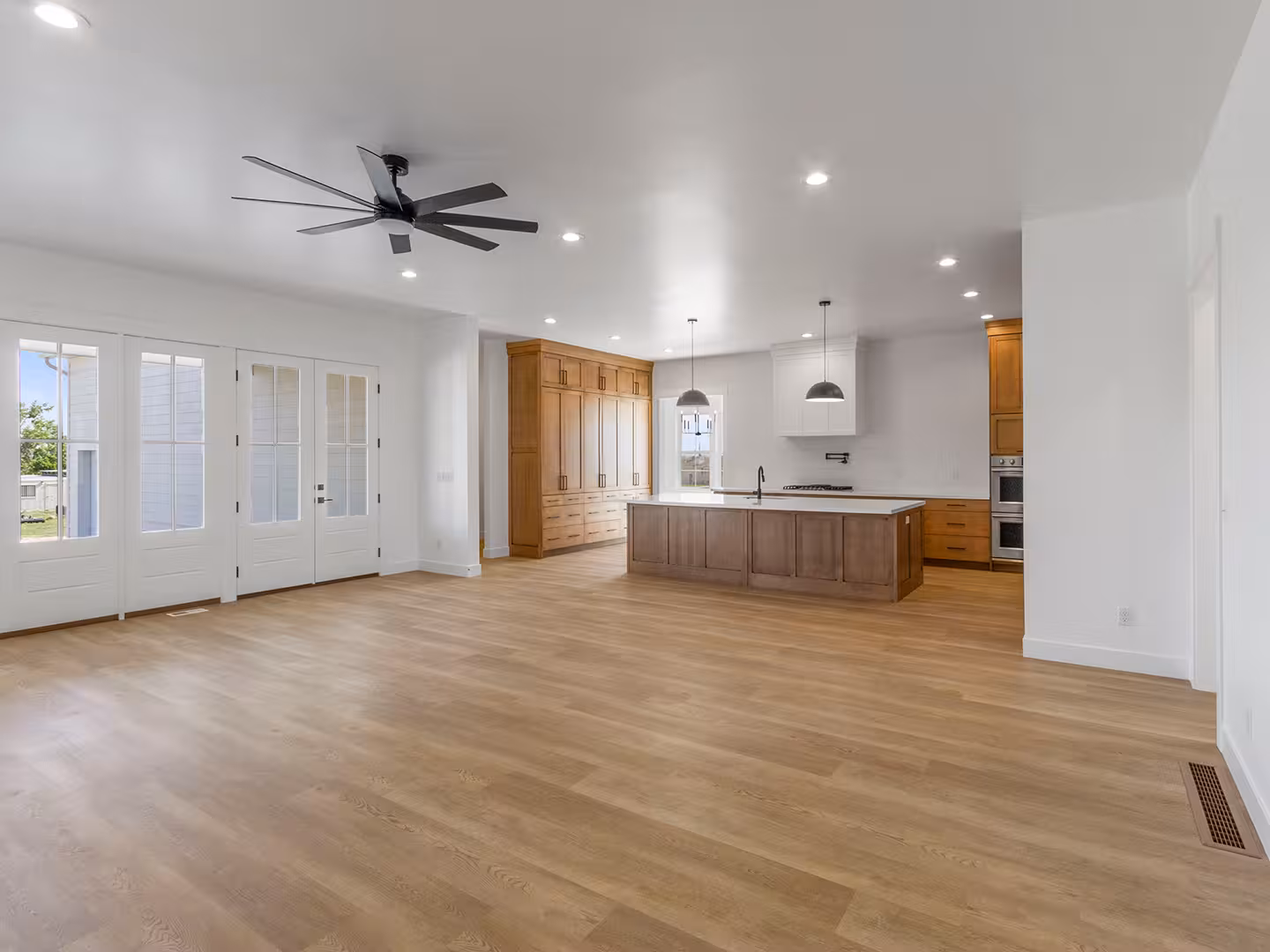 Great room in the Paradise home open to a wood-cabinet kitchen, with French doors along one wall