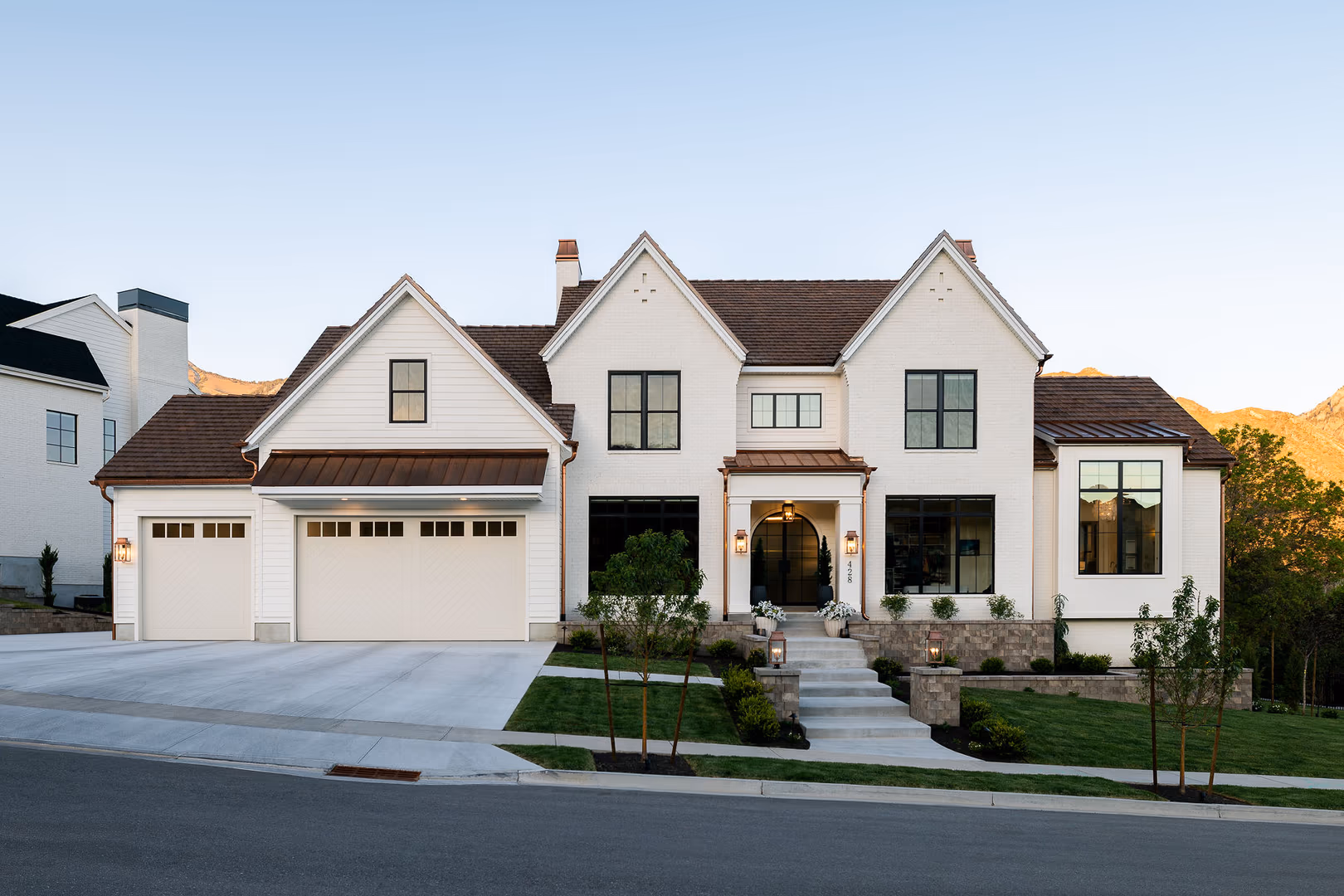 Front of the Perry home with white brick, steep gables, copper accents and an arched entry