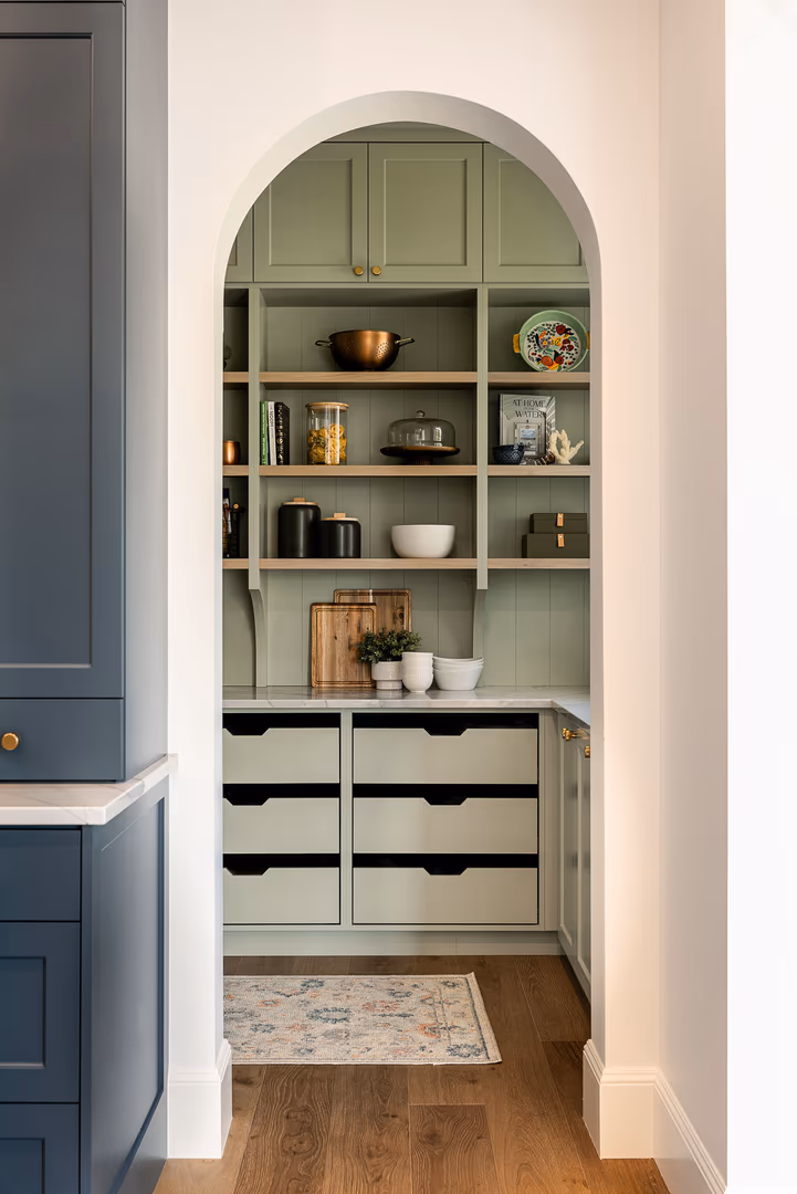 Arched doorway into the sage green walk-in pantry of the Perry home