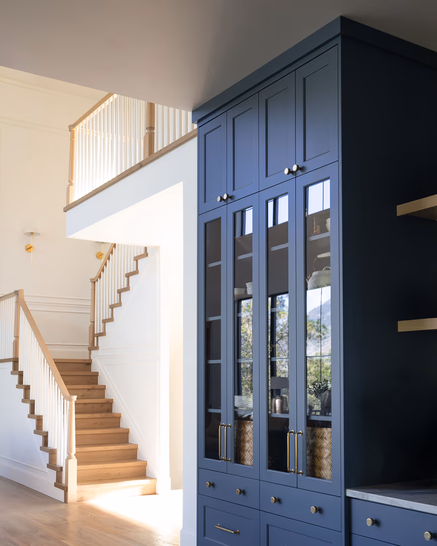 Navy glass-front cabinets beside the open staircase in the Perry home