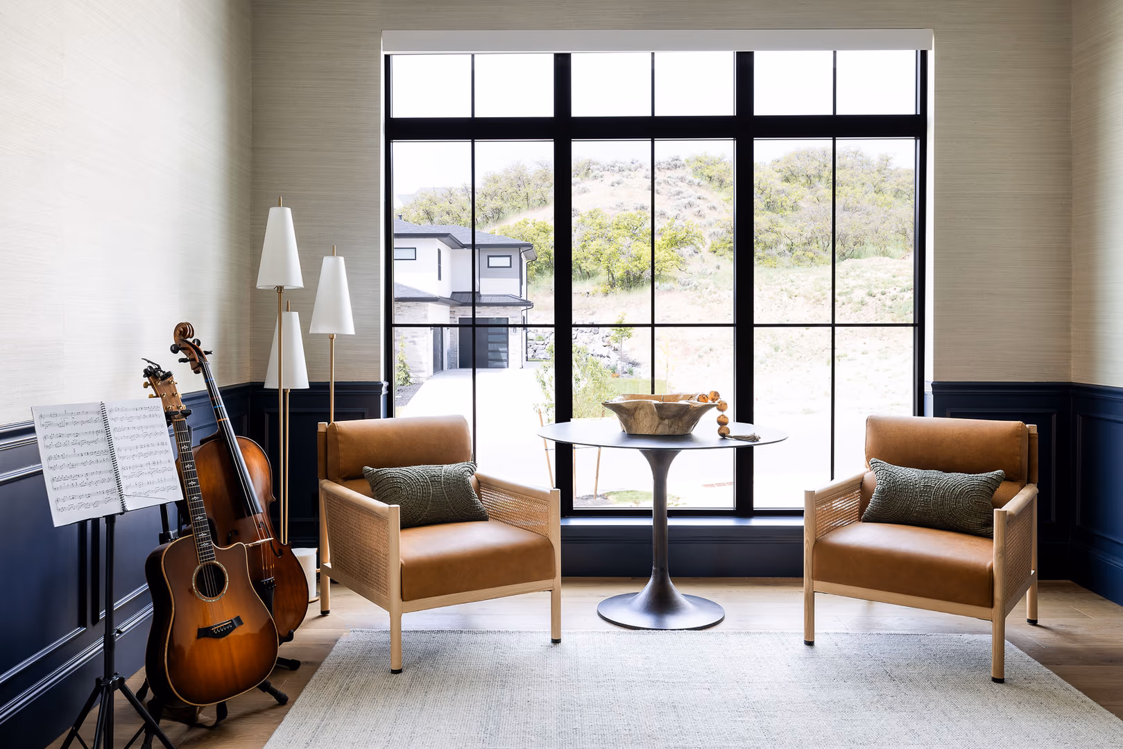 Music room in the Perry home with leather armchairs, navy wainscot and a large black window